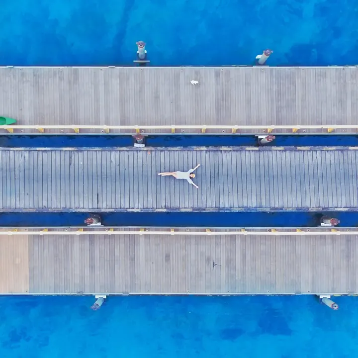 Top-down drone view of a timber pier over blue water off Derawan Island