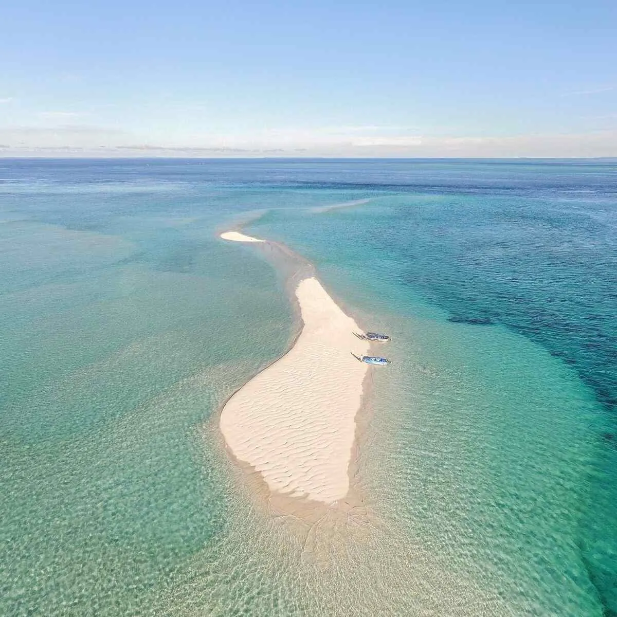 Aerial view of a white sandbar in the clear shallows of the Derawan Archipelago