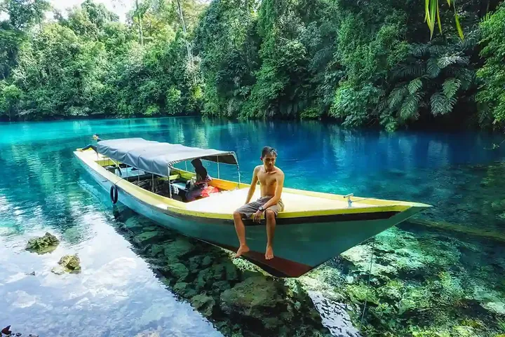 Traveller sitting on the bow of a longboat on Labuan Cermin