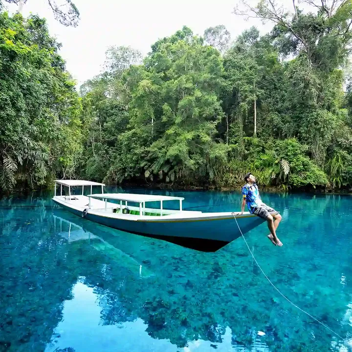 Man standing on the bow of a longboat at Labuan Cermin