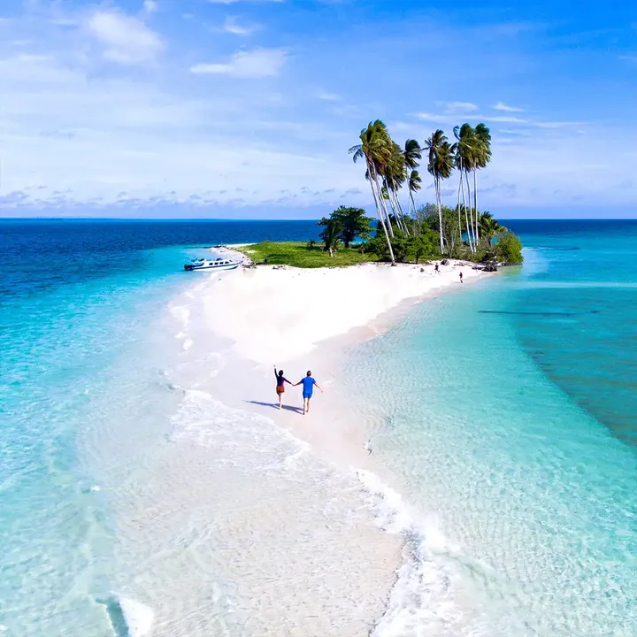 Aerial view of the white sand spit of Manimbora Island with a speedboat at anchor
