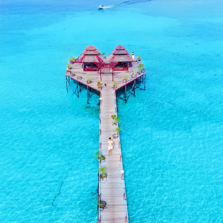 Drone view of the red-roofed jetty pavilion at Maratua over turquoise water