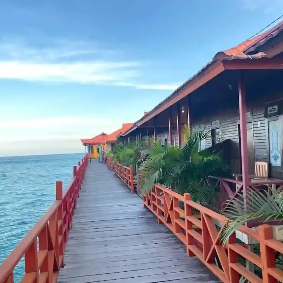 Red timber boardwalk past the water cottages of Reza Derawan Resort